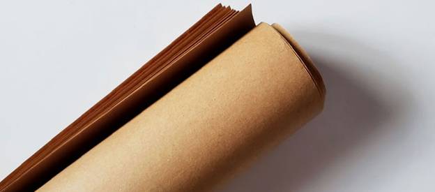 Unfinished brown craft paper and printed cards rolled together for printing and packaging purposes at Starlite Paper & Cards.